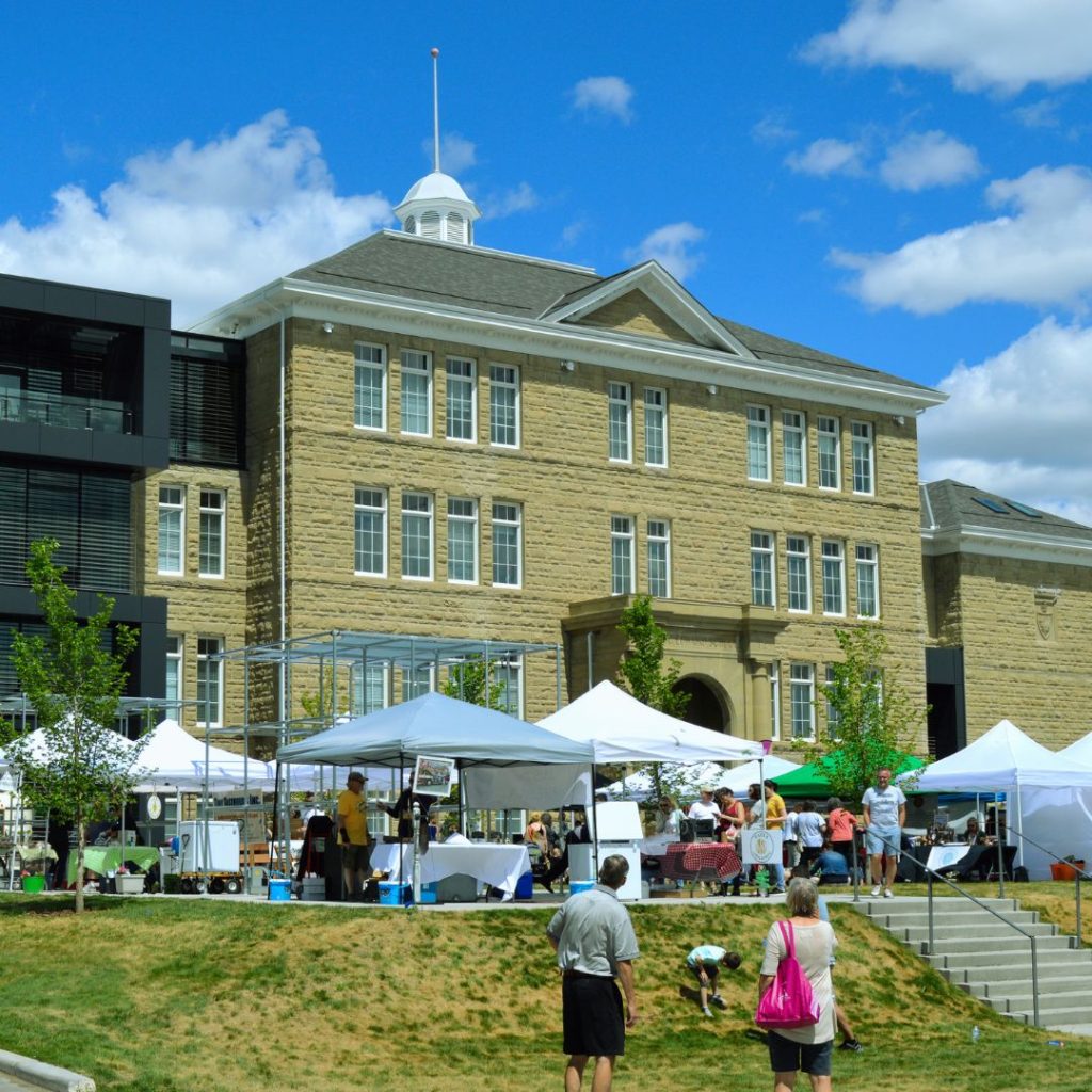 A busy market on the grass in front of a large sandstone building
